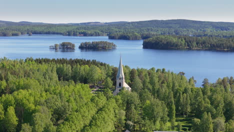 Aerial-of-church-tower-in-Stjarnsund-enveloped-by-lush-trees-near-Lake-Grycken