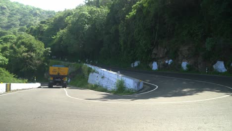 Commercial-truck-driving-in-speed-through-winding-mountain-road,-Hair-pin-bend-road-national-highway-through-forest