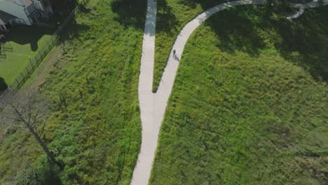 An-aerial-drone-top-down-view-of-ana-adult-male-cyclist-riding-through-Exploration-Green-in-Clear-Lake,-Houston,-Texas