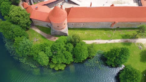 Top-down-view-of-Trakai-Castle-in-Lithuania,-surrounded-by-greenery-and-river