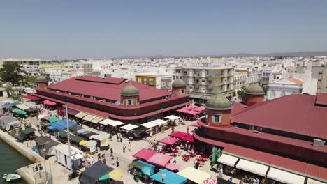 Luftaufnahme-Des-Marktviertels-In-Olhão,-Portugal,-Mit-Historischen-Gebäuden-Mit-Roten-Dächern-Und-Geschäftigem-Straßentreiben