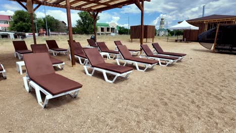 Relaxing-beach-scene-with-white-lounge-chairs-under-a-wooden-pergola