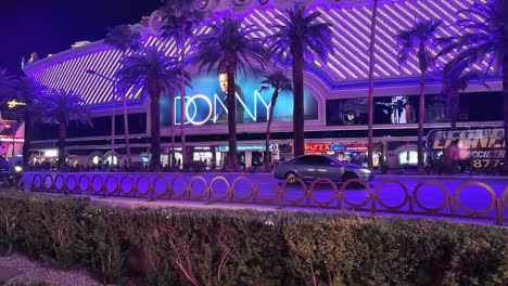 Brightly-lit-evening-scene-with-palm-trees-and-vibrant-signage-on-the-Las-Vegas-Strip