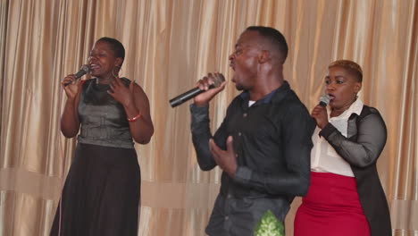 Tres-Cantantes-Actúan-Apasionadamente-En-El-Escenario-De-Kampala,-Uganda.