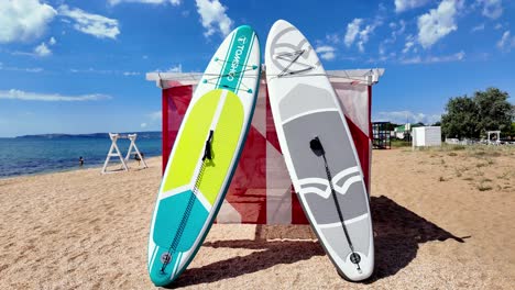 Two-bright-paddleboards-are-leaning-against-a-red-and-white-striped-beach-hut