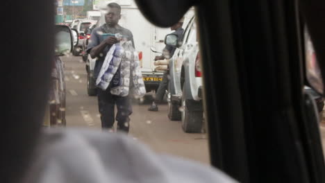 black-african-street-vendor-selling-toilet-papaer-in-the-traffic-jam