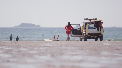 Female-lifeguard-next-to-beach-patrol-truck-keeps-eye-out-on-swimmers-for-safety