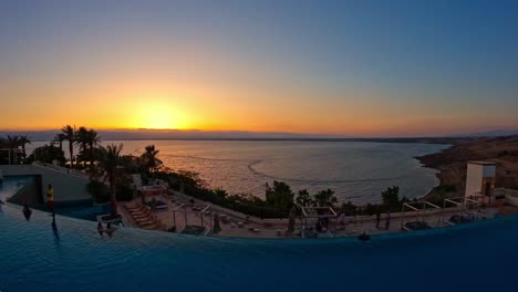 Time-lapse-sun-setting-over-the-Dead-Sea-from-resort-poolside,-Jordan