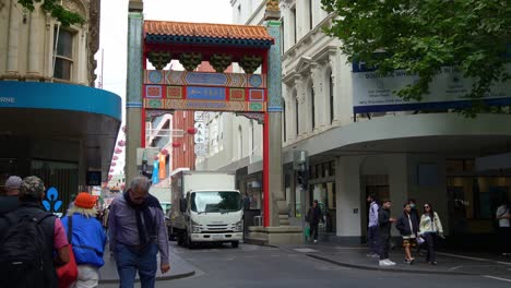 Bustling-downtown-Melbourne-city-featuring-iconic-landmark-Chinatown-with-pedestrians-crossing-on-the-crosswalk-and-vehicle-traffic-along-Little-Bourke-street