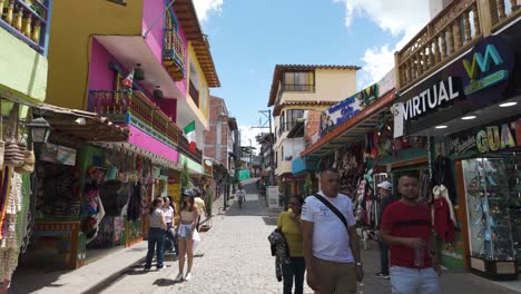 Calle-Vibrante-En-Guatapé,-Colombia,-Con-Coloridos-Edificios,-Tiendas-Y-Gente-Caminando.