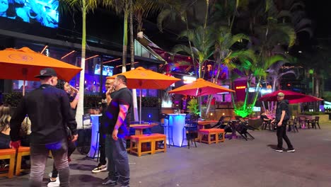 Vibrant-nightlife-scene-in-El-Poblado,-Medellin,-Colombia,-with-people-enjoying-outdoor-seating-under-bright-umbrellas