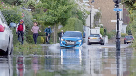 Coche-Empujado-A-Través-De-Agua-Estancada-Que-Inundó-La-Carretera-Del-Barrio-Residencial