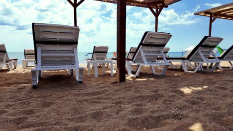 A-row-of-empty-beach-chairs-sit-on-a-sandy-beach-in-Crimea-under-a-wooden-canopy-on-a-sunny-day