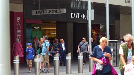 People-shopping-at-the-David-Jones-flagship-store-in-bustling-downtown-Melbourne-city-with-pedestrians-strolling-on-Bourke-Street-Mall,-static-shot