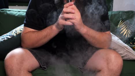 A-man-takes-a-drag-from-an-e-cigarette-and-blows-out-a-cloud-of-smoke