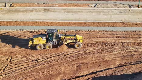 Vista-Aérea-Cercana-De-Una-Niveladora-Nivelando-Grandes-Montones-De-Tierra-En-Un-Nuevo-Sitio-De-Construcción-Residencial