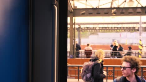 Woman-walks-and-smiles-as-she-walks-out-of-a-train-cabin-in-Prague,-green-travel