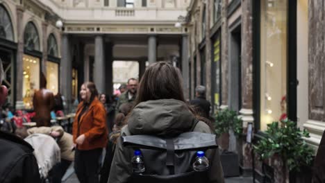 Fashionable-Woman-walks-through-the-city-center-of-brussels-following-her-passing-shops-in-a-mall-tracking-shot-slow-motion