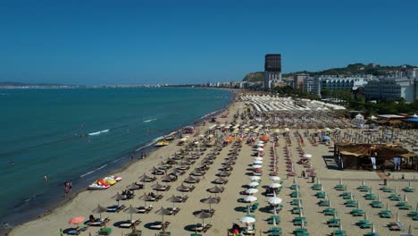 Tourists-sunbathe-and-relax-on-the-serene,-sunny-beach-with-sand-along-the-Adriatic-Sea-in-Durres,-Albania