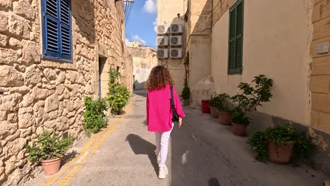 A-person-walks-along-the-sunlit,-narrow-streets-of-Mdina,-Malta,-embracing-the-essence-of-historic-charm-and-Mediterranean-ambiance