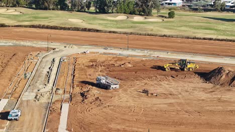 Aerial-overview-of-a-grader-levelling-dirt-at-a-new-construction-site