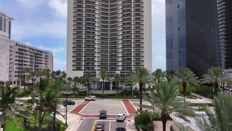 Aerial-tilt-up-flight-over-busy-street-in-downtown-of-Sunny-Isles-Beach-City-In-Florida,-USA