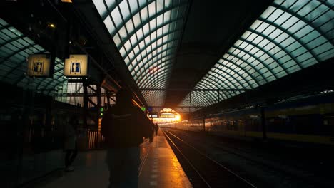 Amsterdam-Central-Station-platform-is-beautifully-lit-by-orange-hues-of-sunset,-creating-a-deep,-long-perspective