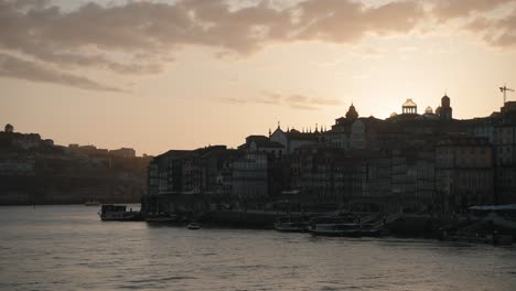 Portos-Uferpromenade-Bei-Sonnenuntergang-Mit-Silhouetten-Von-Gebäuden-Vor-Einem-Goldenen-Himmel,-Portugal