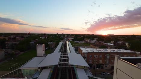 aerial-drone-view-of-Chicago-sunset-over-an-urban-landscape-with-a-train-line-leading-into-the-horizon