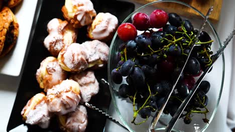 Sweetened-buns-with-white-glaze-and-grapes-in-glass-bowl-on-reception-table