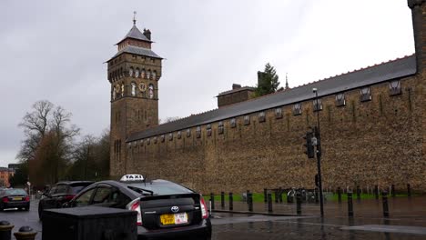 Cars-driving-next-to-Cardiff-Castle-on-a-rainy-day-in-Cardiff,-Wales