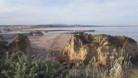 Clifftop-view-of-Praia-da-Batata-beach-with-people-enjoying-the-sand-and-ocean,-Lagos