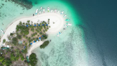 Colorful-Tour-Boats-Aligned-Around-Pass-Island-Sandbank-in-Coron,-Drone-Top-Down