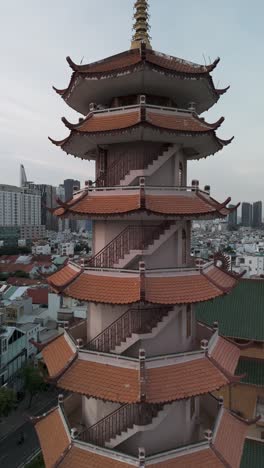 Buddhist-temple-or-pagoda-prayer-tower-in-late-afternoon-light-with-city-skyline-and-urban-sprawl-of-Ho-Chi-Minh-City,-Vietnam