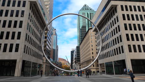 Urban-Circular-Sculpture-Surrounded-By-Buildings-In-Downtown-Montreal-City,-Wide-Angle