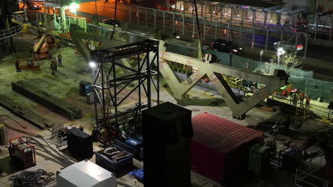 AERIAL:-Crane-lifting-a-heavy-steel-fence-at-a-construction-site-in-illuminated-New-York