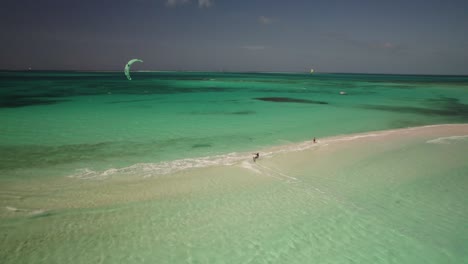 Kiteboarder-gliding-over-crystal-clear-waters-at-a-tropical-beach