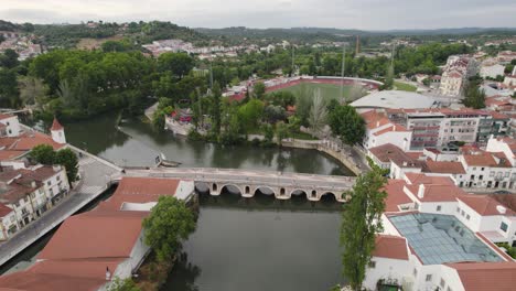 Tomar,-Portugal-Mit-Malerischem-Flussufer,-Historischer-Brücke-Und-üppigem-Grün,-Luftaufnahme