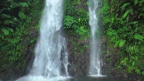 Aerial-close-up-of-waterfall-falling-down-green-mountain-face-wall-on-tropical-island