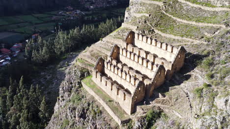 Panorámica-Aérea-De-Alto-ángulo-A-La-Izquierda-Del-Sitio-Histórico-De-La-Ciudad-De-Ollantaytambo-Cortada-De-La-Ladera-En-Perú