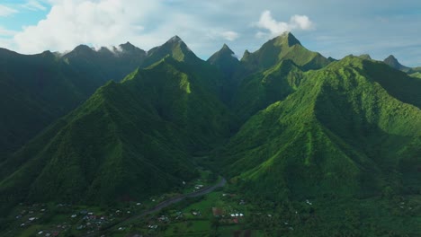 Late-afternoon-sunset-green-island-mountain-peaks-Teahupoo-Tahiti-French-Polynesia-aerial-drone-town-village-Paris-summer-Olympics-venue-Mount-Orohena-Aorai-Ronui-blue-sky-river-valley-forward-motion