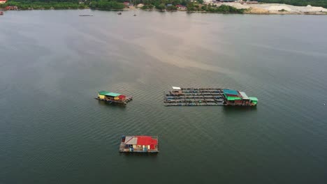 Traditional-aquaculture-floating-fish-farms,-breeding,-rearing,-and-harvesting-of-fish-and-shellfish-in-water-environments,-with-cages-and-nets-teeming-with-marine-life,-connected-by-wooden-walkways