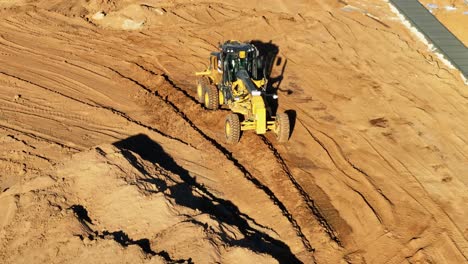 Close-front-on-aerial-view-of-a-grader-levelling-deep-soil-at-a-new-residential-construction-site