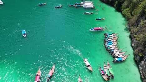 Busy-Pileh-Lagoon-of-Phi-Phi-Island-Crowded-with-Tour-Boats,-Drone-Tilt-Reveal