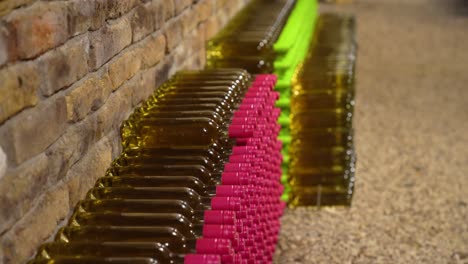 Slow-Motion-Close-Shot-of-White-Wine-Bottles-Arranged-in-a-Brick-Cellar