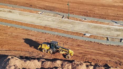 A-grader-working-with-deep-piles-of-dirt-at-a-new-residential-building-site