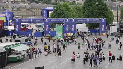 Busy-fanzone-entrance-to-public-viewing-in-Stuttgart,-Germany-during-Euro-2024,-static-while-people-passing-by-or-sitting-on-stairs