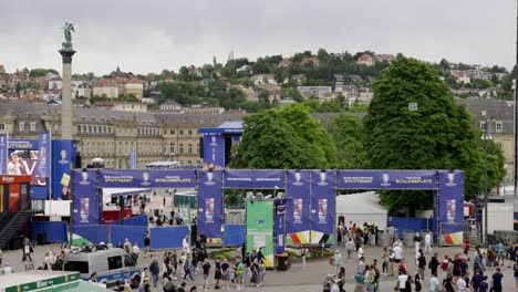 Busy-fanzone-entrance-to-the-Schlossplatz,-Jubilee-Column-for-public-viewing-in-Stuttgart,-Germany-during-Euro-2024-with-police-car-and-hills-with-trees-in-the-background