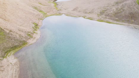 Clear-blue-lake-in-the-rocky-highlands-of-Iceland,-aerial-view