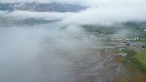 Vuelo-Aéreo-Sobre-La-Región-De-Glen-Coe-En-Un-Día-Muy-Nublado,-Hacia-El-Puente-Y-La-Carretera,-Escocia